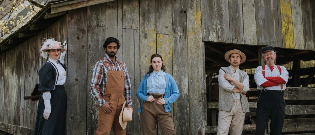 The Re-enactors troupe posing in front of a heritage barn