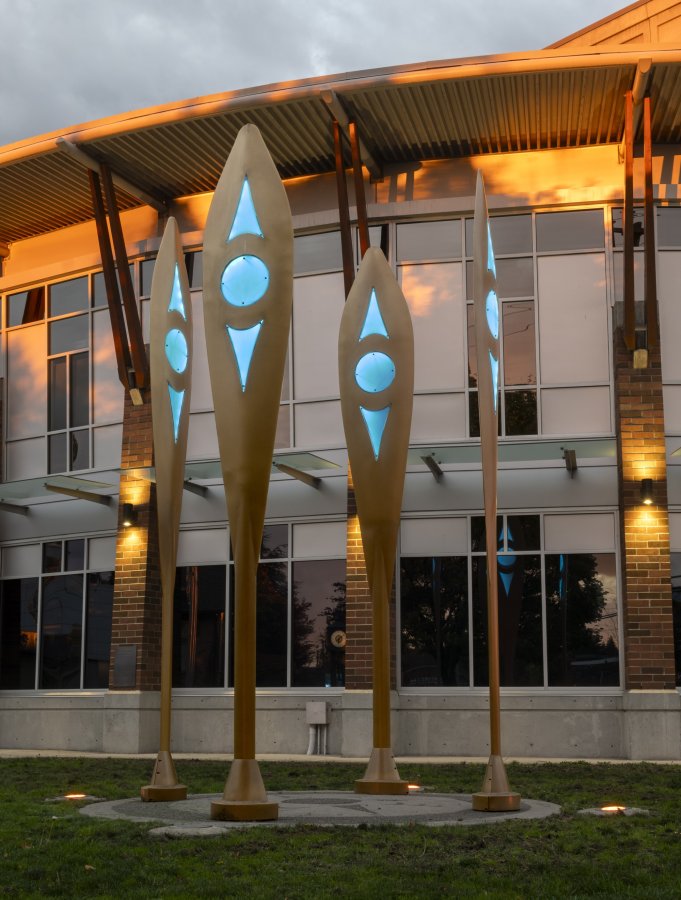 Four wooden paddles lit up in orange point to the sky from the ground