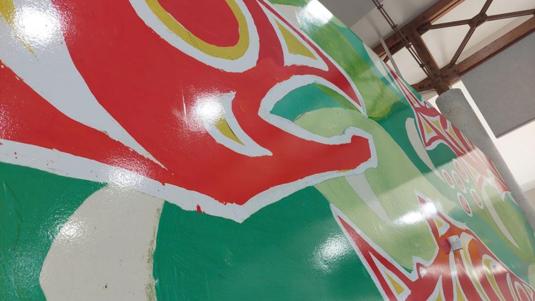 Green and red Indigenous fish mural on a library wall