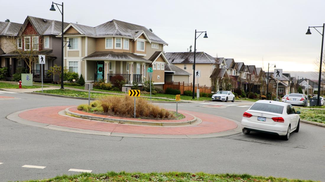 traffic circle with vegetation with a vehicle going around it