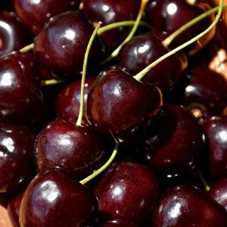 A cluster of Lapins cherries, deep red and glossy, piled together in a wooden basket.
