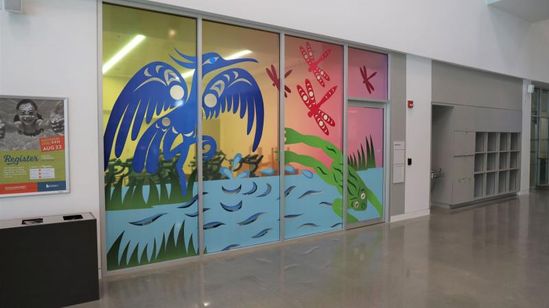 Colourful Indigenous art of dragonflies, a frog, and a heron on an indoor window