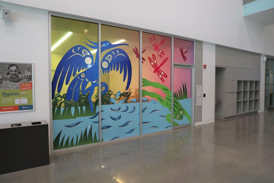 Colourful Indigenous art of dragonflies, a frog, and a heron on an indoor window