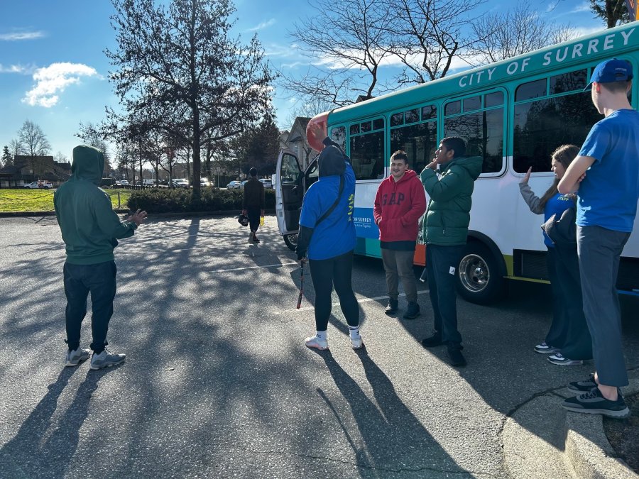 People waving goodbye in front of a bus.
