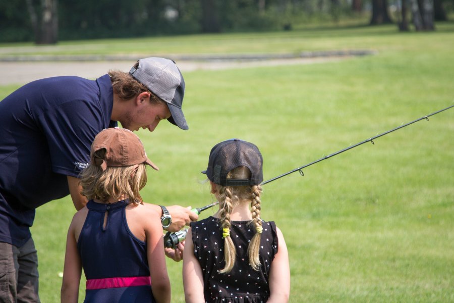 Instructor teaching children how to use a fishing rod."