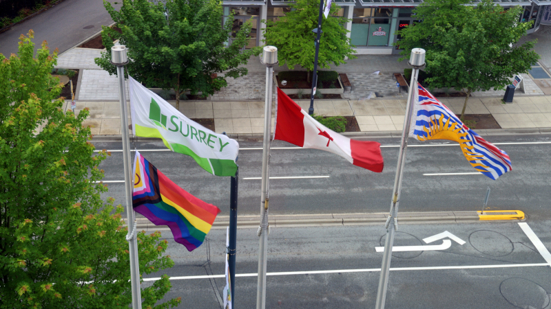 Pride flag, City of Surrey flag, Canada flag, and British Columbia flag