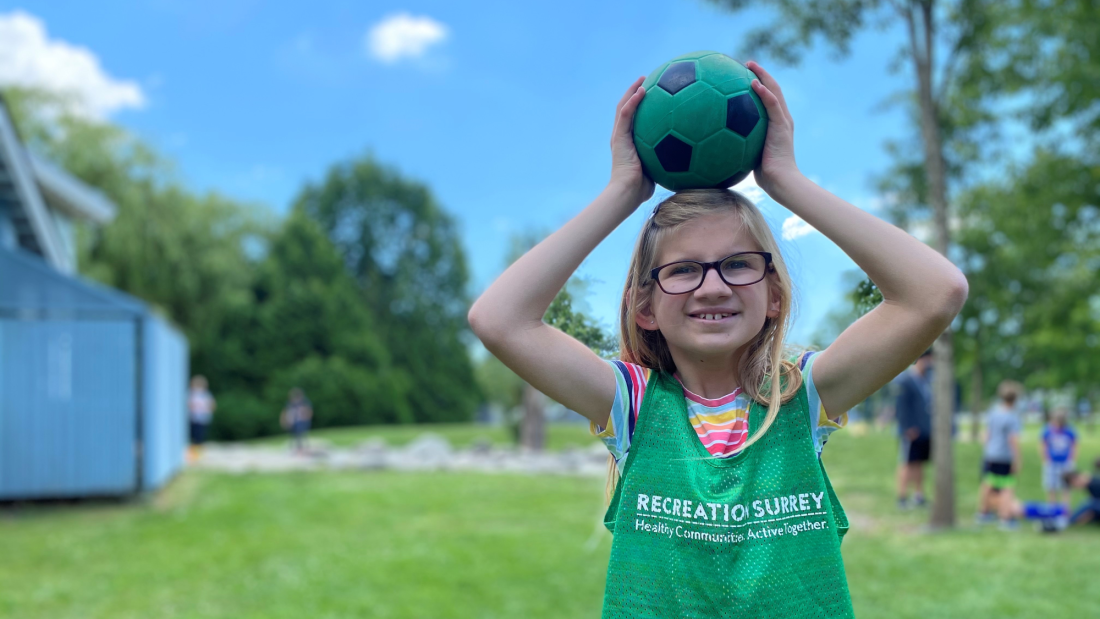 a young girl holding a green ball