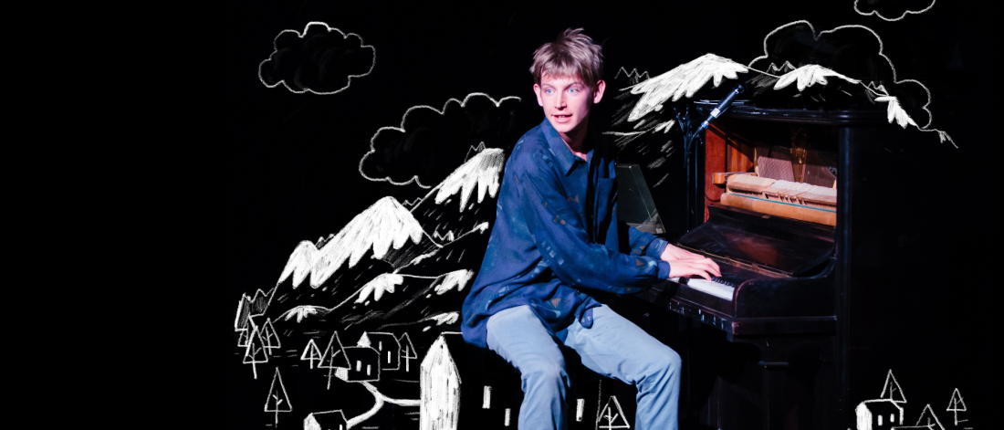 Actor sitting at the piano surrounded by an illustrated city and mountains