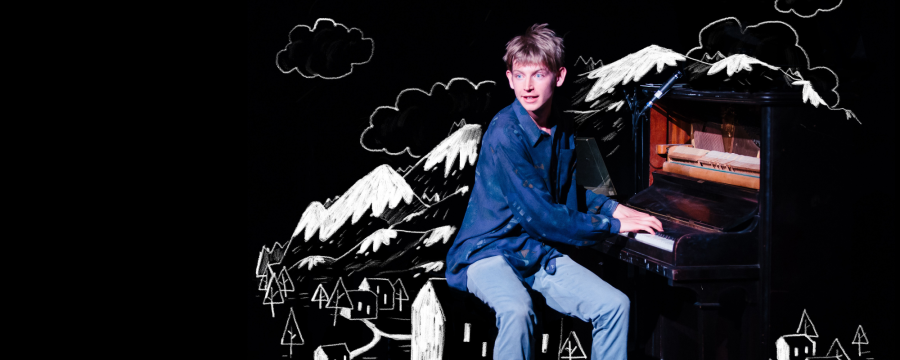 Actor sitting at the piano surrounded by an illustrated city and mountains