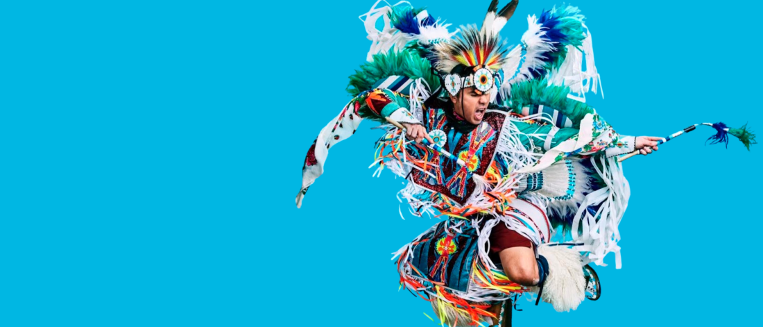 Dancer Notorious Cree aka James Jones in full colourful regalia on a bright light blue background